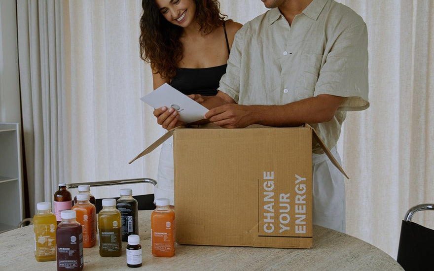Lächelndes Paar packt eine DALUMA Saftkur-Box mit bunten kaltgepressten Säften aus