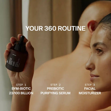 Eine Frau hält eine Hautpflegeflasche vor einer Person mit rasiertem Kopf. Text: Ihre 360-Routine für die Hautbarriere umfasst die Pflegeschritte Sym-biotic, DALUMA PREBIOTIC PURIFYING GESICHTSSERUM und Facial Moisturizer.