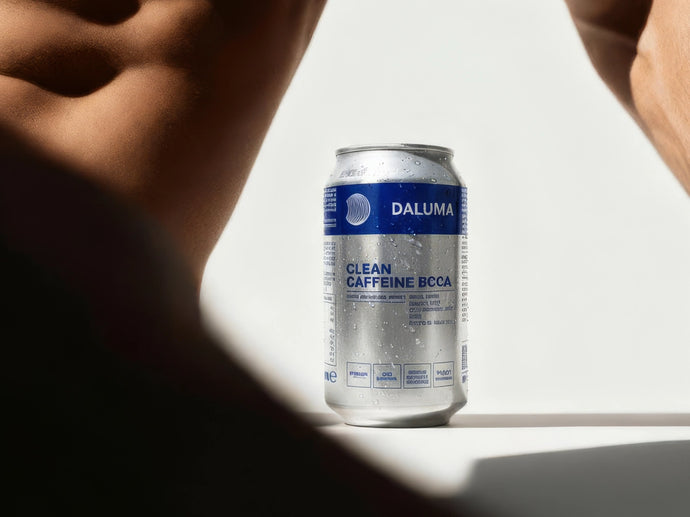 Eine gekühlte, mit Wassertröpfchen bedeckte Dose Daluma Clean Caffeine BCAA steht auf einer weißen Fläche mit schattigen, muskulösen Oberkörpern, die teilweise auf beiden Seiten im Hintergrund zu sehen sind.