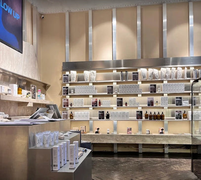 Ein modernes, minimalistisches Ladeninnere mit ordentlich organisierten Regalen, in denen Hautpflege- und Schönheitsprodukte, Flaschen und Schachteln ausgestellt sind. Der Raum zeichnet sich durch neutrale Farben, schlichte Metallakzente und einen sauberen, aufgeräumten Look aus.