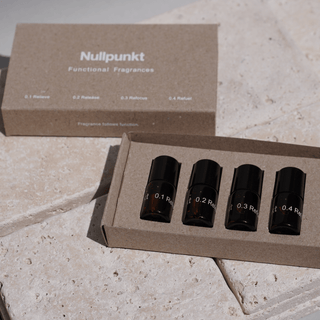 Das NULLPUNKT DISCOVERY SET von Nullpunkt besteht aus vier kleinen Braunglasflaschen - 0.1 Relieve, 0.2 Release, 0.3 Refocus und 0.4 Refuel - in einer Markenbox, die auf einer hellen Steinoberfläche präsentiert wird.